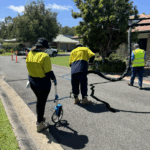 Road maintenance workers measuring cracks and applying sealant on asphalt road